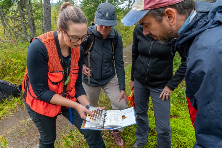 Four people standing around a book